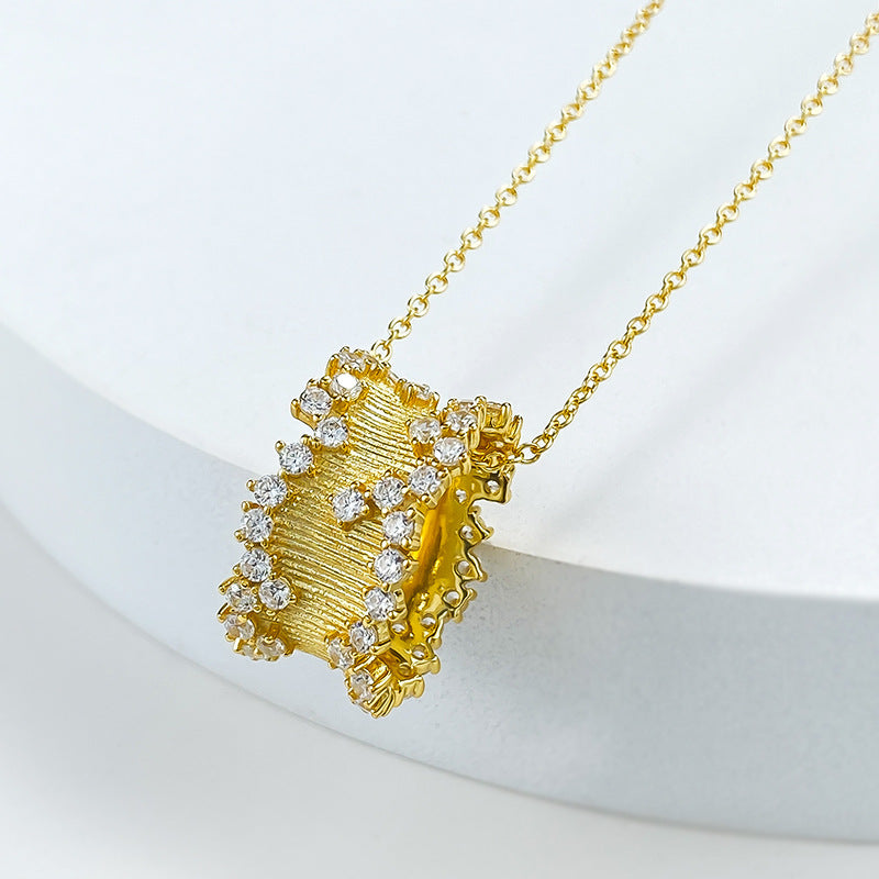 Golden hourglass pendant necklace in brushed gold with cubic zirconia, symbolizing elegance and resilience.