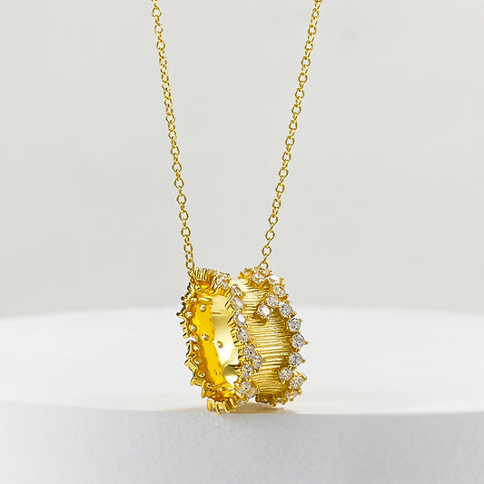 Golden hourglass pendant necklace in brushed gold with cubic zirconia embellishments, exuding elegance and modern charm.