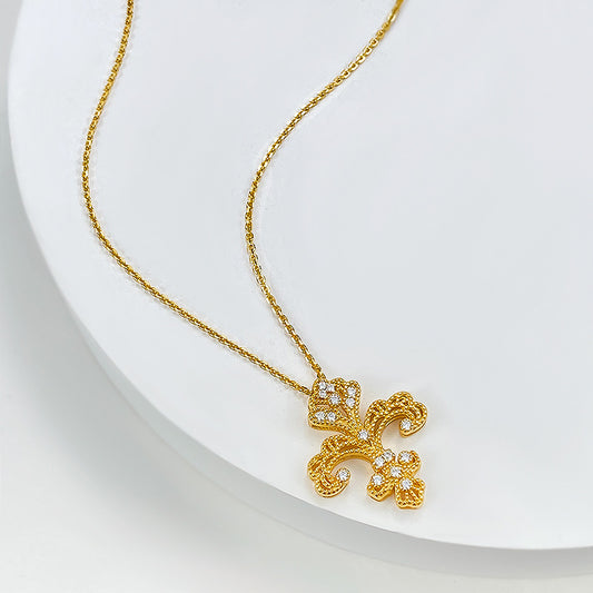 Baroque gold fleur-de-lis pendant necklace with cubic zirconia accents on a delicate chain.