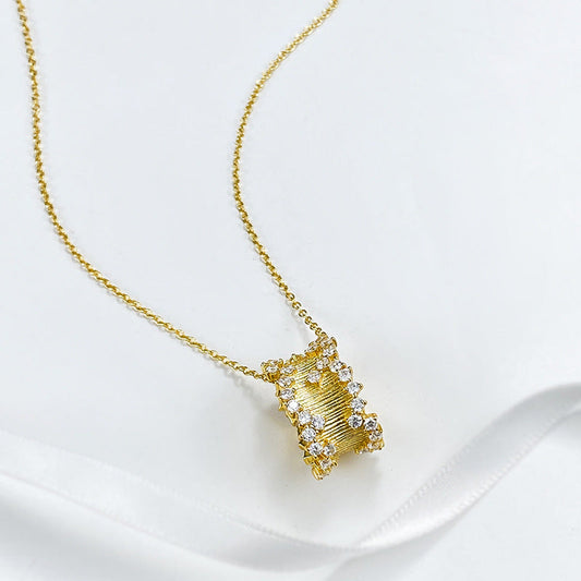 Golden hourglass pendant necklace in brushed gold with cubic zirconia, symbolizing elegance and strength.